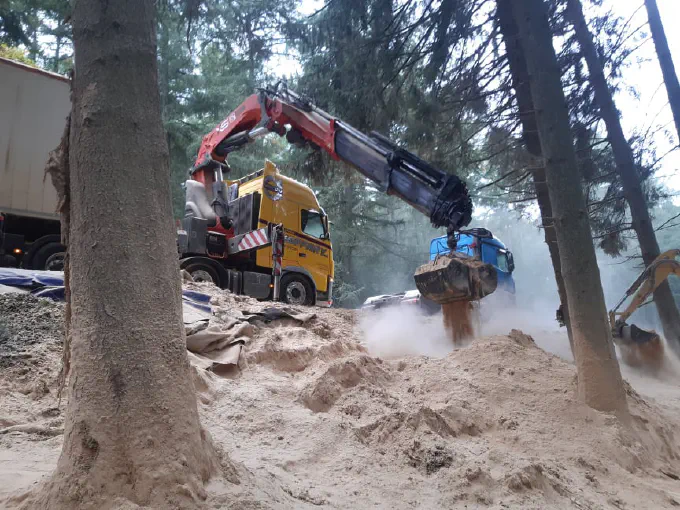 Camion-grue avec benne preneuse en action en forêt