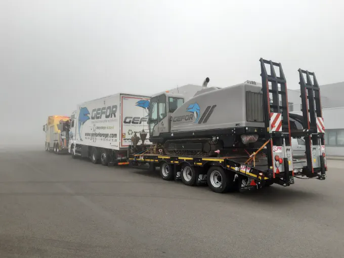 Camion et remorque porte-engin remorqués dans le brouillard