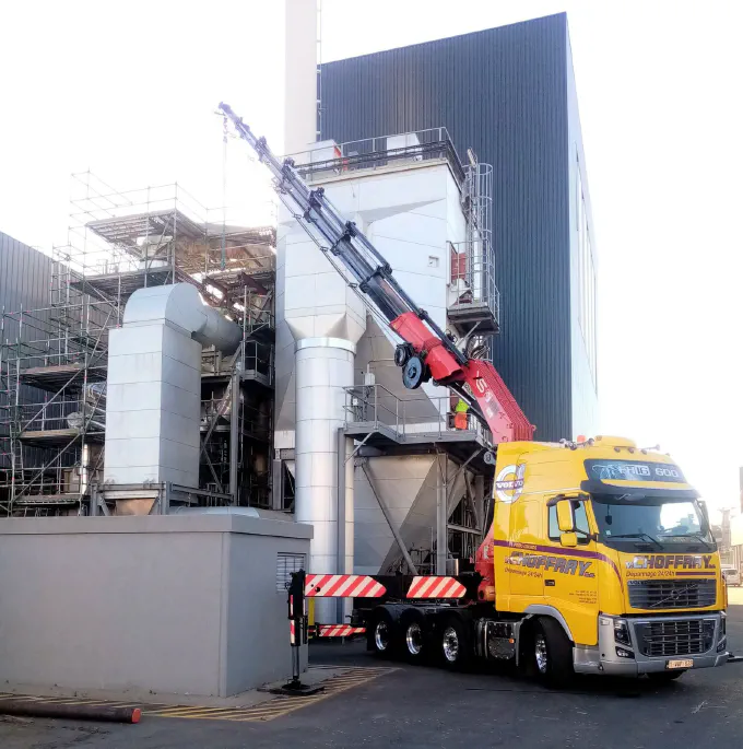 Le tracteur-grue déployé contre un bâtiment industriel