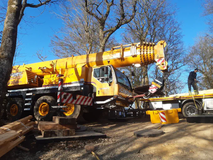 La grue calée sur madriers pour un levage en forêt