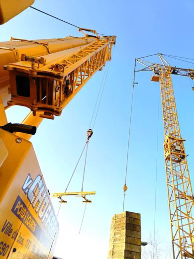 Grue télescopique levant un palonnier sur chantier