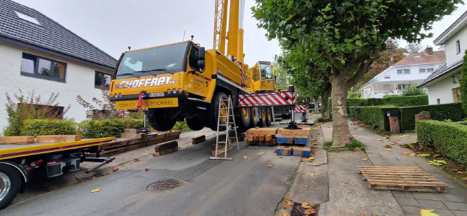 La grue calée sur madriers dans une rue résidentielle