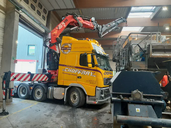 Le tracteur-grue manœuvre dans un hall industriel