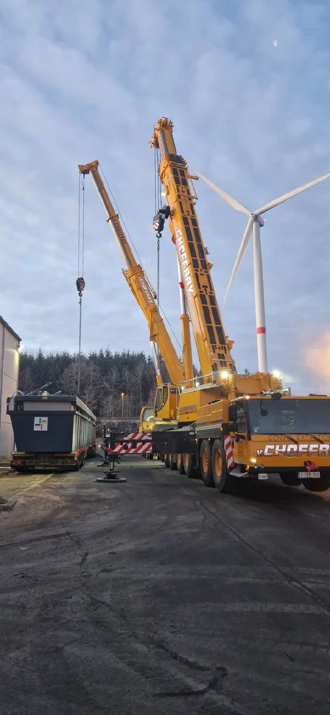 Deux grues au pied d'une éolienne