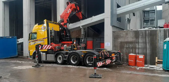 Le tracteur-grue stabilisé devant un hall industriel