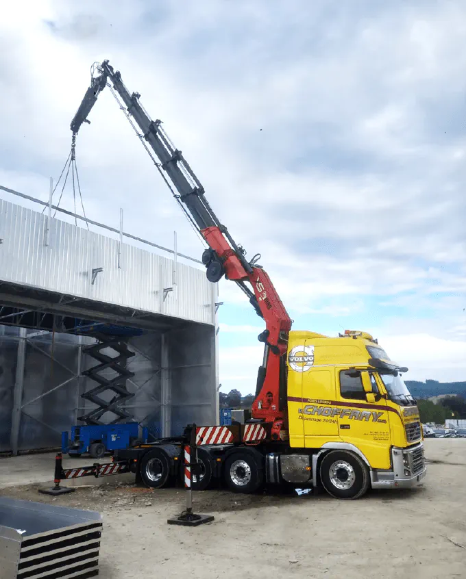 Le tracteur grue Volvo, fly jib déployé au-dessus d'un hall